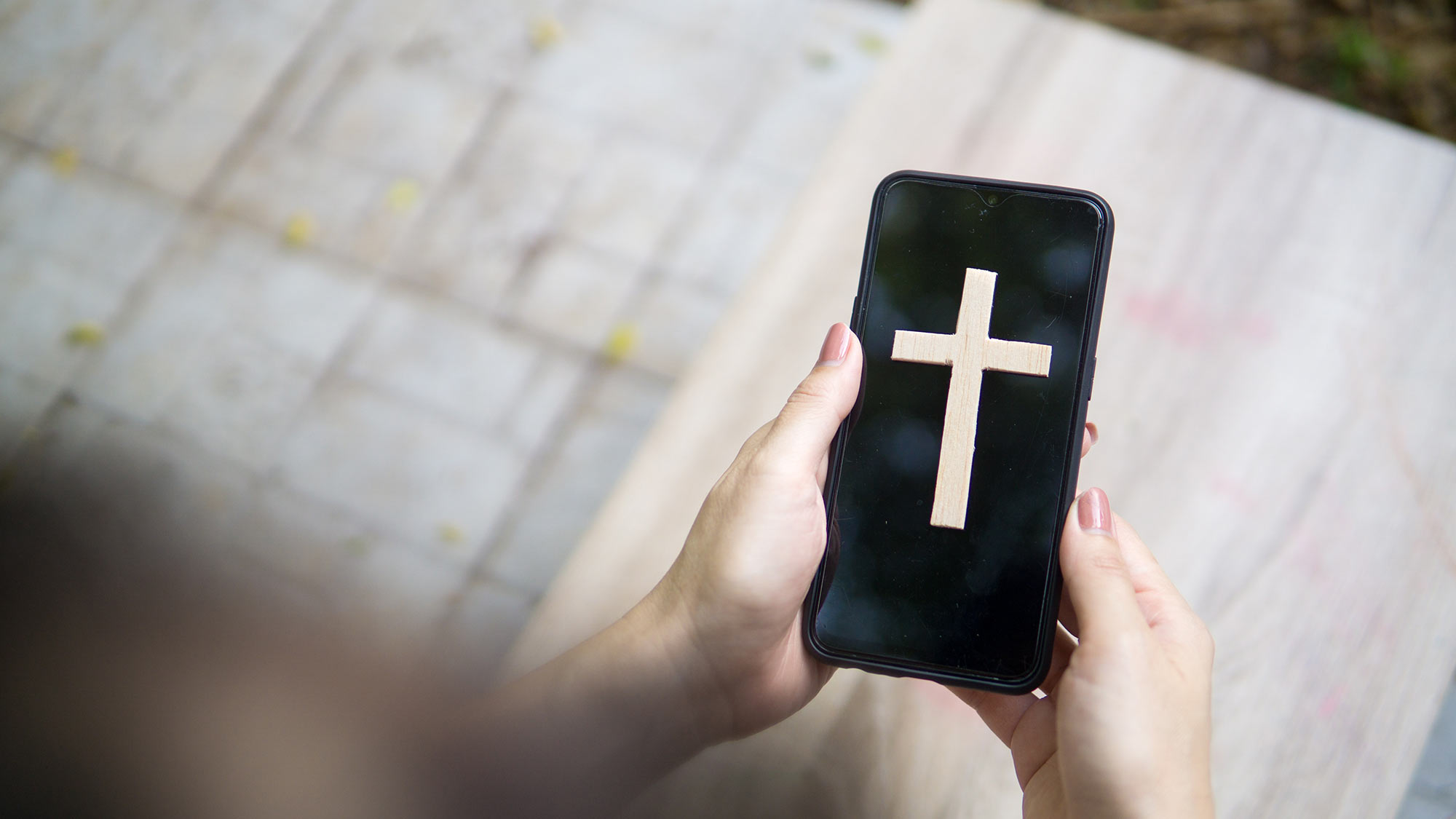 Closeup of a smartphone with a Christian cross on the screen.