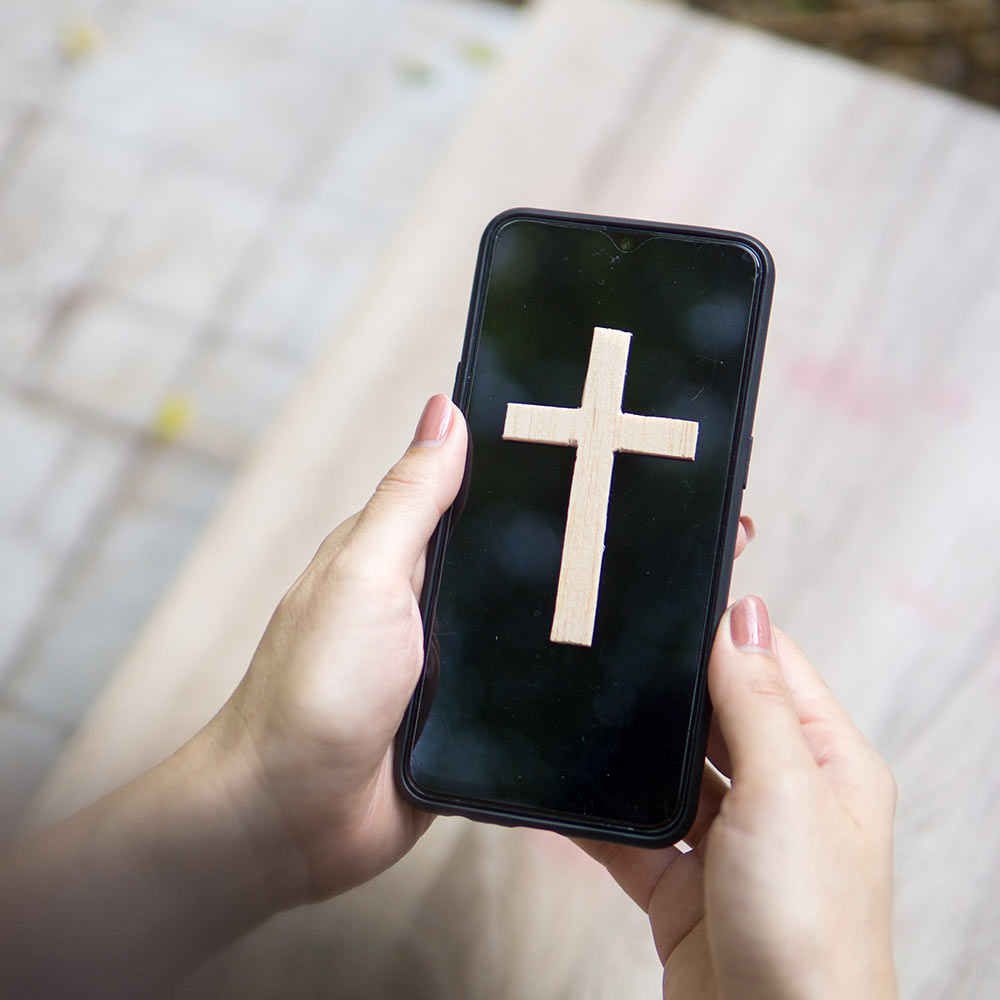 Closeup of a smartphone with a Christian cross on the screen