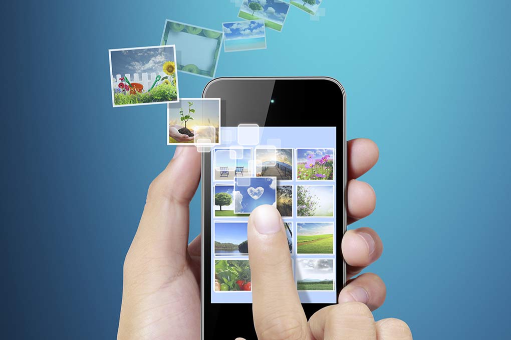 A finger swipes images on a smartphone screen to symbolize the images that can be sent with MMS text messaging.